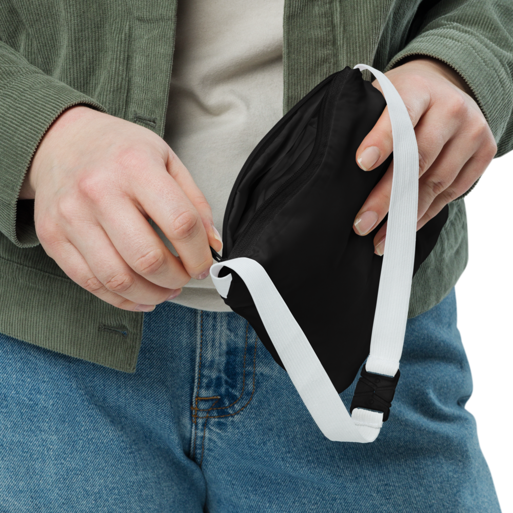 Persona mostrando el Cortavientos Negro Unisex VOOM — The Motion Code doblado en su bolsa con cierre y correa blanca ajustable.
