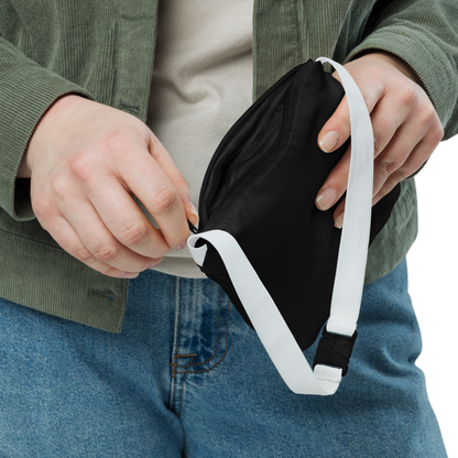 Persona mostrando el Cortavientos Negro Unisex VOOM — The Motion Code doblado en su bolsa con cierre y correa blanca ajustable.