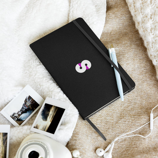 Cuaderno de Tapa Dura VOOM — The Archive Code sobre manta beige junto a fotos instantáneas y bolígrafo celeste