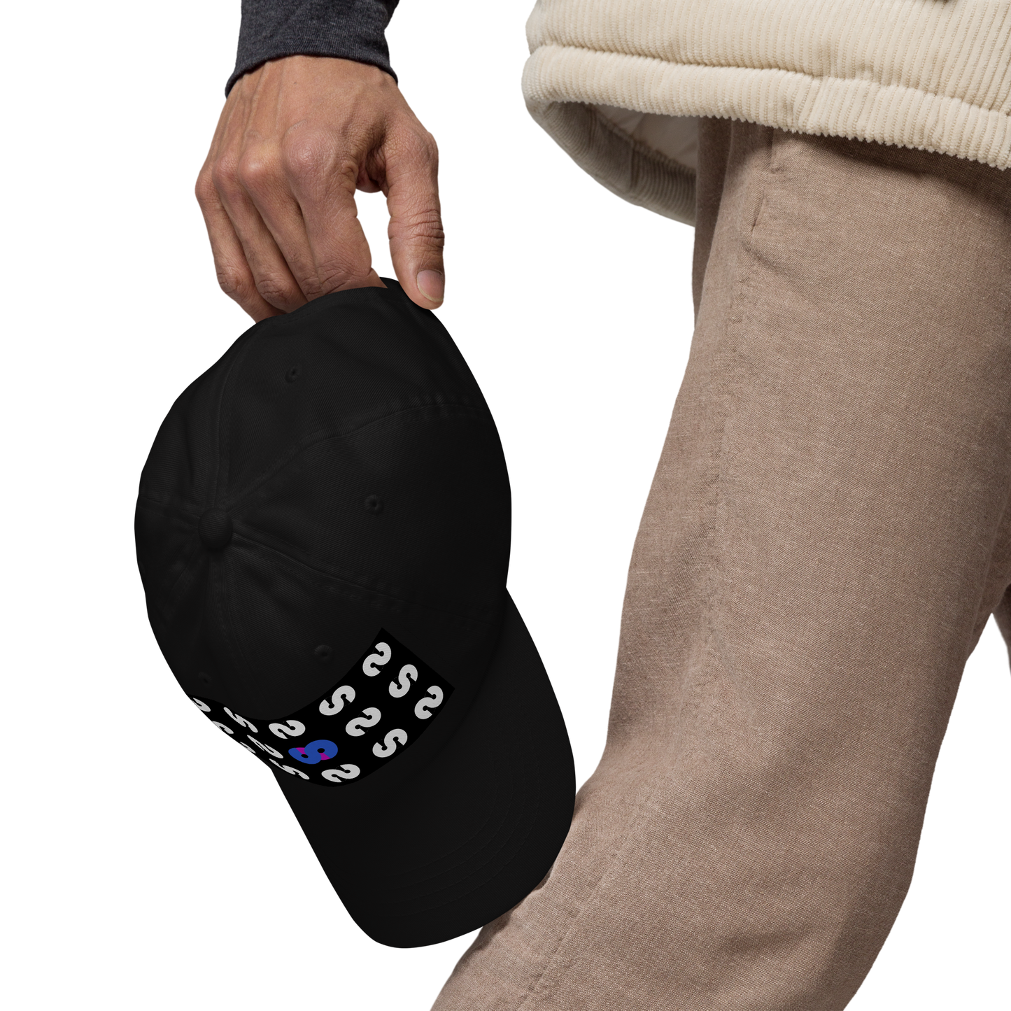 Persona sostiene la Gorra Negra VOOM — The Pattern Code mostrando detalle del símbolo azul y patrón repetitivo en visera curvada.