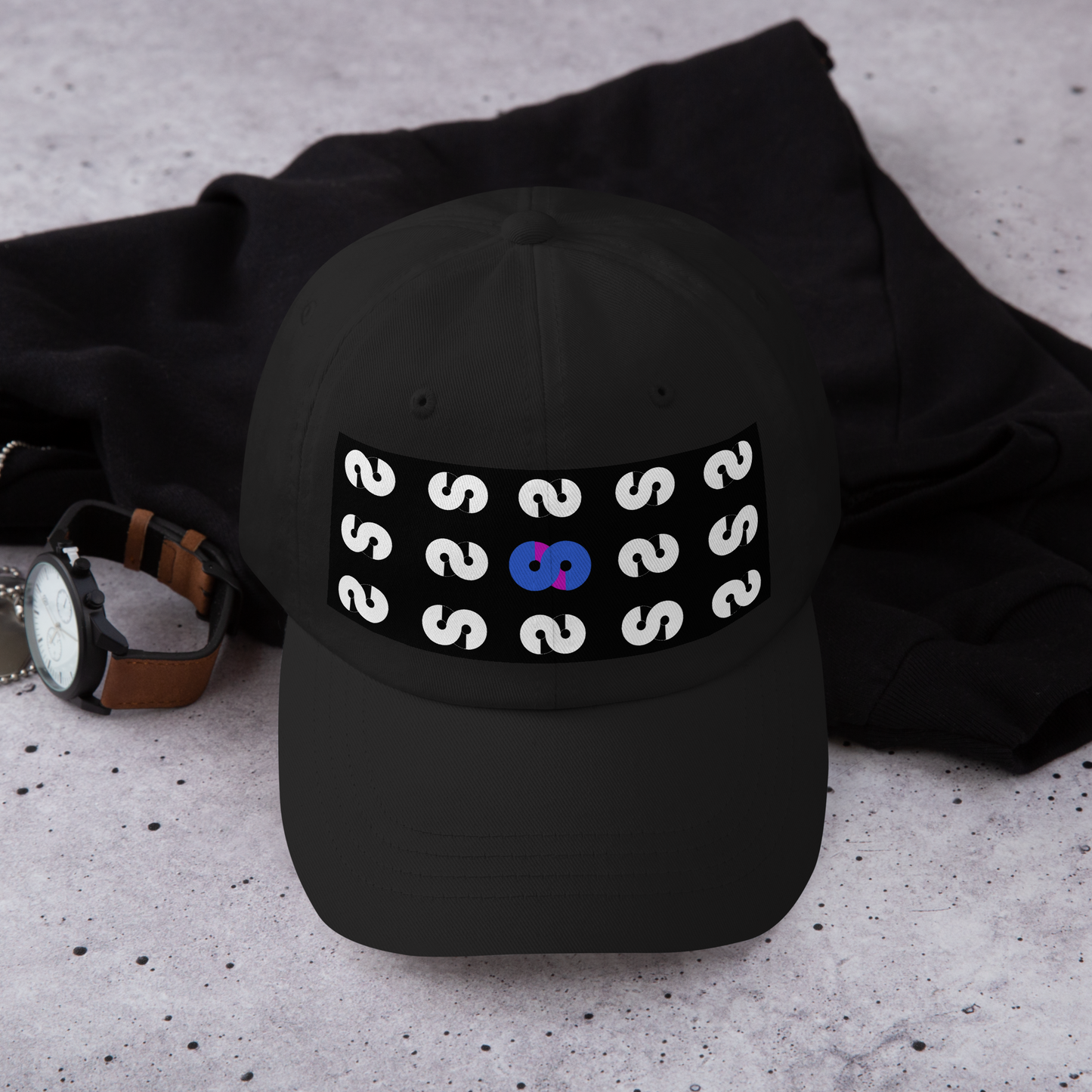 Gorra Negra VOOM — The Pattern Code con diseño frontal de patrón repetitivo en blanco y símbolo central azul y rojo.