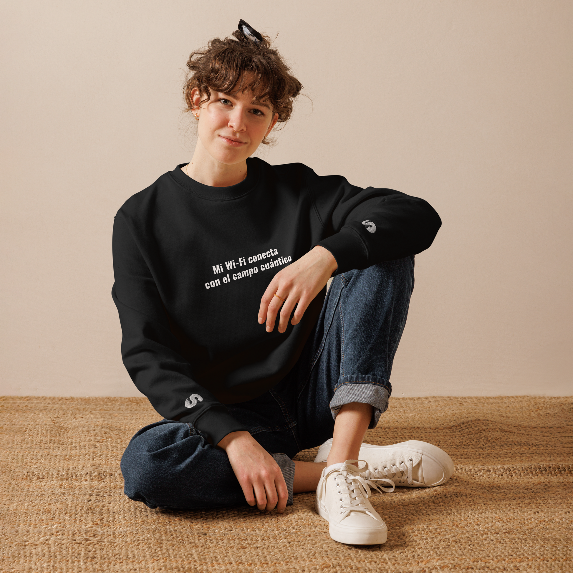 Mujer sentada con Sudadera Eco VOOM — Quantum Field Connection negra y texto blanco “Mi Wi-Fi conecta con el campo cuántico”