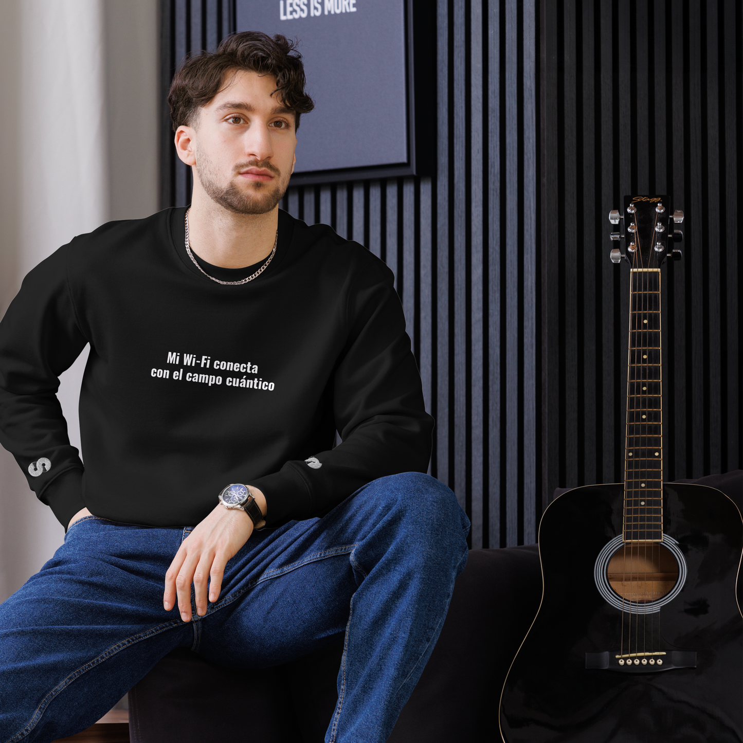Hombre sentado con Sudadera Eco VOOM — Quantum Field Connection negra y texto blanco "Mi Wi-Fi conecta con el campo cuántico