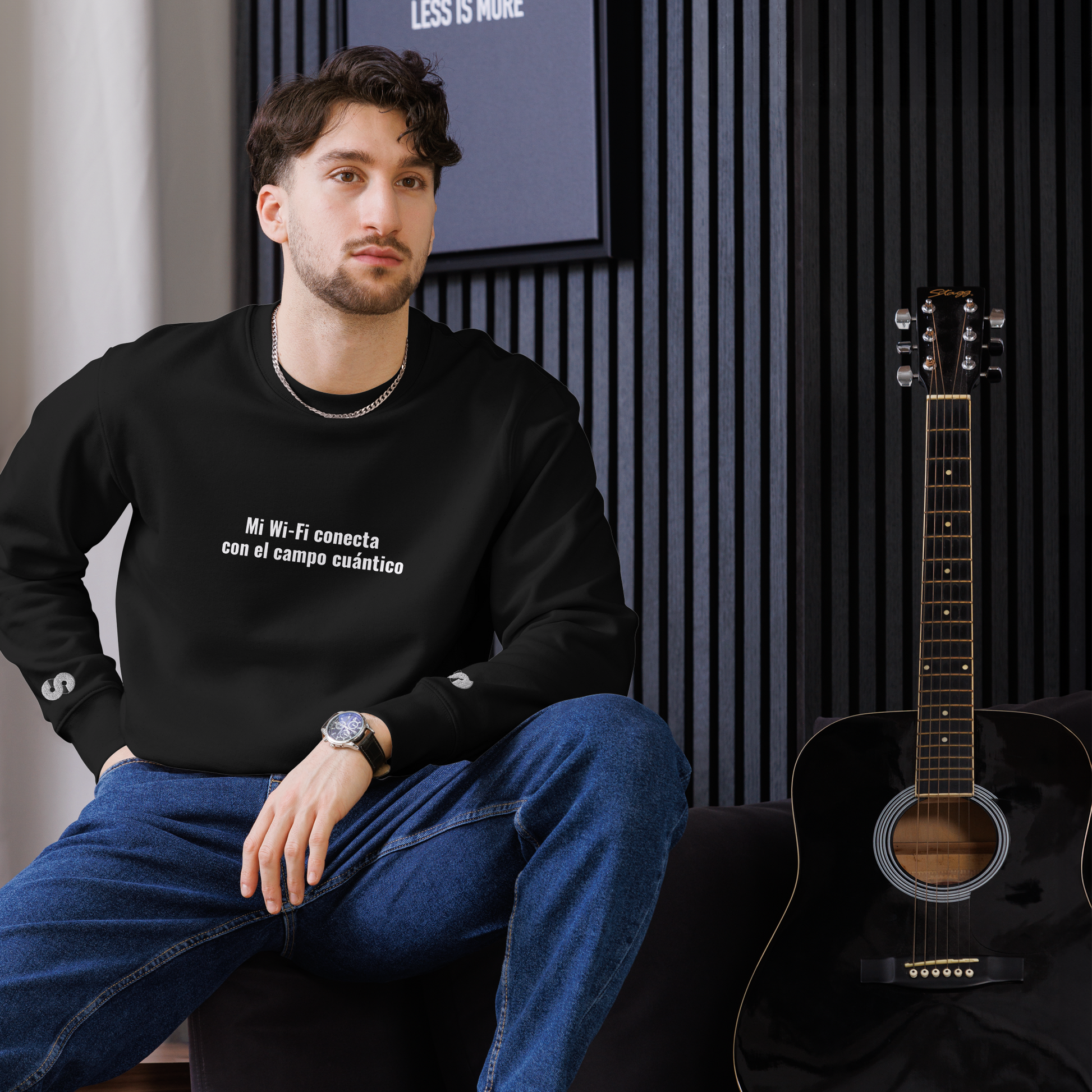 Hombre sentado con Sudadera Eco VOOM — Quantum Field Connection negra y texto blanco "Mi Wi-Fi conecta con el campo cuántico